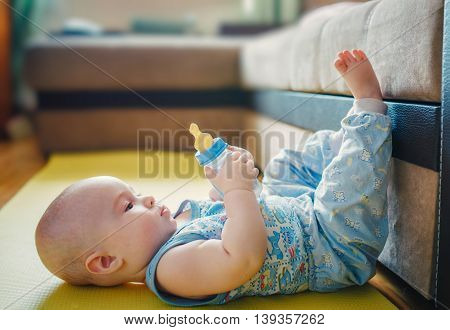 baby lying on the floor with your feet up and holding a bottle of water