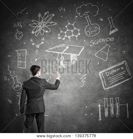 Rear view of man drawing education concept on blackboard with chalk