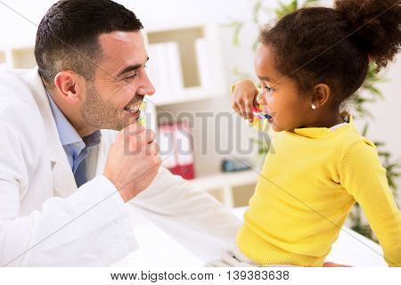 Specialist Pediatrician Shows To Child How To Brush Teeth