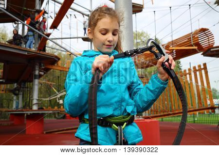 Happy pretty girl holds safety rope near Rope way on special playground