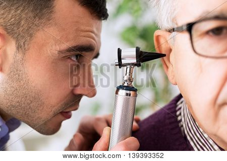 Otologist Looking Through Otoscope