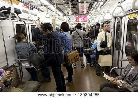 TOKYO- CIRCA MAY, 2016: Passengers traveling by Tokyo metro. Business people commuting to work by public transport in rush hour. Shallow depth of field photo