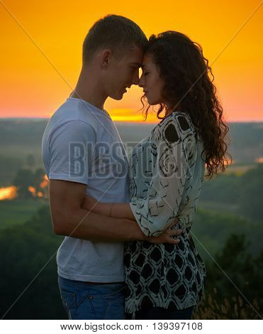 romantic couple at sunset on bright yellow sky background, love tenderness concept, young adult people