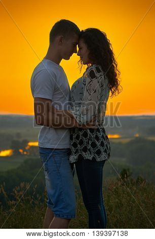 romantic couple at sunset on bright yellow sky background, love tenderness concept, young adult people