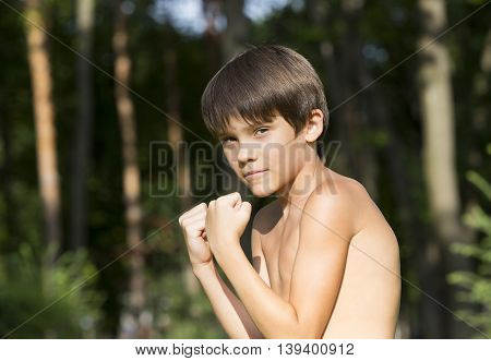 portrait of a boy in nature which shows his muscles