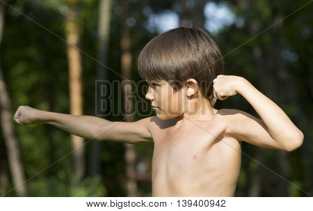 portrait of a boy in nature which shows his muscles