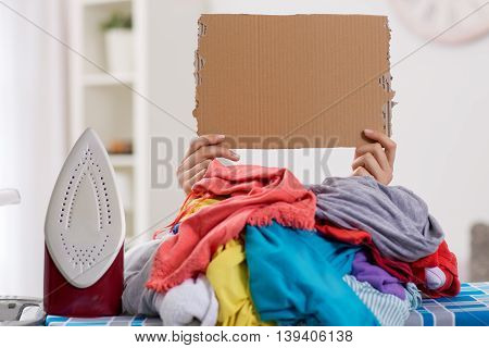 Woman ironing needs help hidden by large pile of laundry