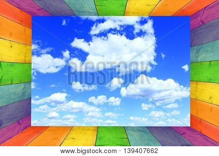 multicilored frame on the blue sky background with great white clouds