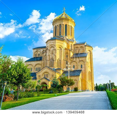 The beautiful stone Sameba Cathedral located on the hill among the lush green garden Tbilisi Georgia.