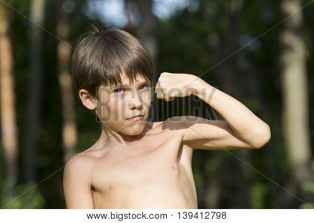 portrait of a boy in nature which shows his muscles