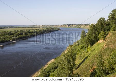 View from the high bank of the wide river. The bridge in the distance