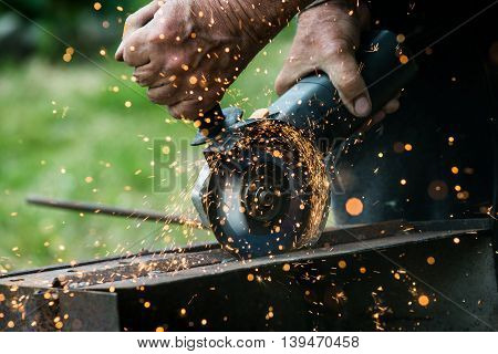 Closeup of worker using a grinder on a metal plate