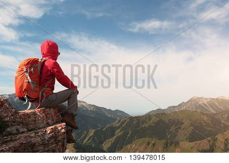 successful woman backpacker enjoy the view on mountain peak cliff