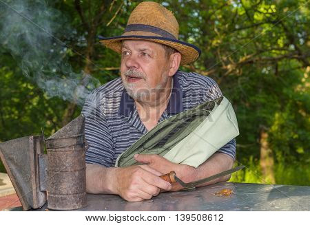 Outdoor portrait of positive bearded elderly man bee-keeper