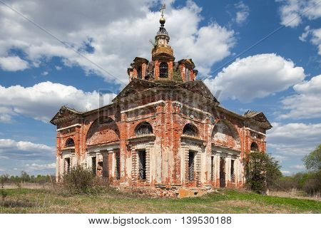 Abandoned old brick church in the countryside on the background of blue sky with clouds