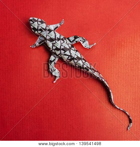 Origami paper art wild lizard on a red paper background