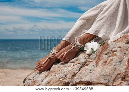 closeup photo of beautiful young bride legs with anklets with beach background