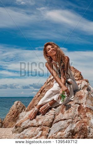 happy young woman sitting on the rock on the beach