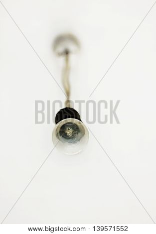 Dusty light bulb hanging from the ceiling below up view.