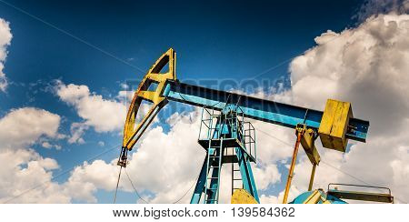 Oil and gas well profiled on blue sky with cumulus clouds