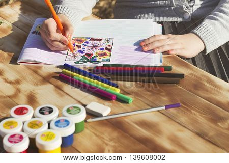 The girl draws the patterns with a Sharpie on the album. Front view