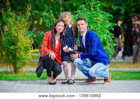 Mother and father brings little daughter to school.