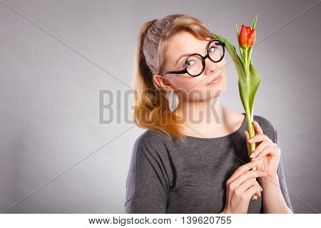 Delicacy and subtlety of women. Young adorable woman with spring flower. Portrait of beauty delicate girl in glasses with red beautiful tulip.