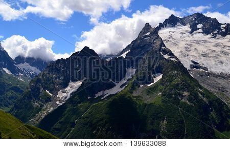 Mountain peaks against a background of white clouds. Dombay - Karachay-Cherkessia in the basin of the Teberda in the North Caucasus (Russia). Photo taken on: July 26 Friday 2013