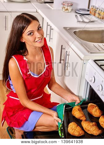 Young woman bake croissants at home kitchen. Woman oven croissants at kitchen.