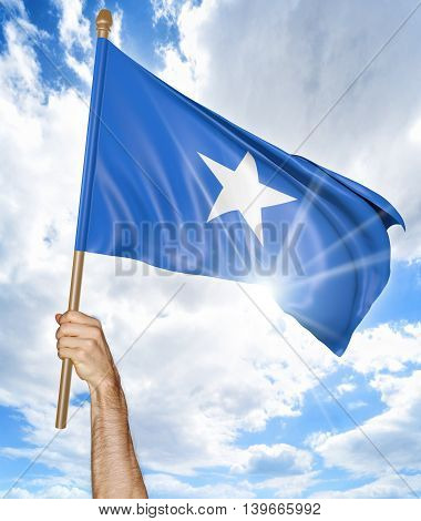 Person's hand holding the Somalian national flag and waving it in the sky, 3D rendering