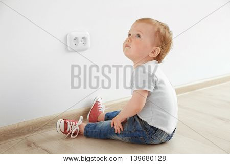Baby playing with electrical outlet on floor at home