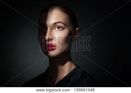 Fashion model with pink lips with half face covered with shadow.Isolate.Black background