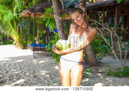 Photo young girl relaxing on beach with coconut. Smiling woman spending chill time outdoor summer Bali island. Horizontal picture