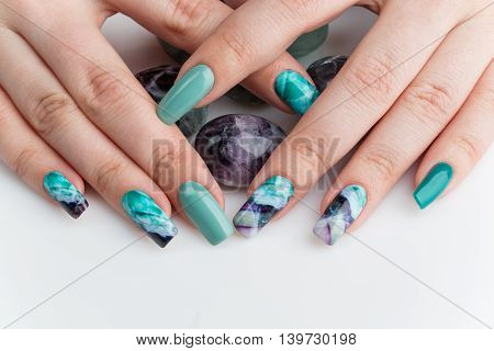 Closeup of woman nails with creative purple and green manicure. Fluorinit print. Copy space.