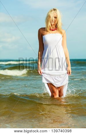 Leisure spare time activities. Young woman chilling out on the beach. Lady spending free moments outside. Attractive girl has white dress.