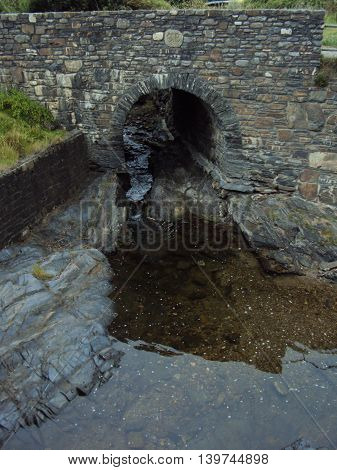Bridged river towards beach photographed at Crackington Haven in Cornwall