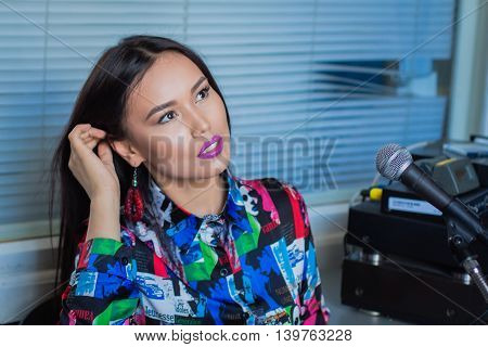 Beautiful girl in headphones with a microphone on the radio in the studio