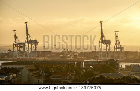 FREMANTLE,WA,AUSTRALIA-JUNE 25,2016: Fremantle port with large gantry cranes, sea containers and the Indian Ocean at sunset in Fremantle, Western Australia.