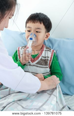 Asian Boy Having Respiratory Illness Helped By Health Professional With Inhaler.