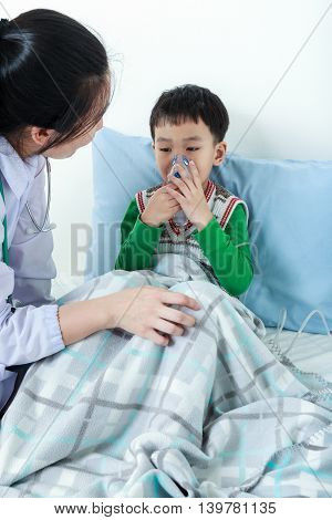 Asian Boy Having Respiratory Illness Helped By Health Professional With Inhaler.