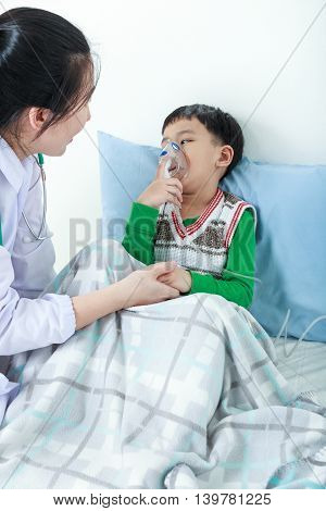 Asian Boy Having Respiratory Illness Helped By Health Professional With Inhaler.