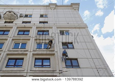 RUSSIA MOSCOW - JUNE 18 2015: Team of construction climbing workers reconstructing the facade of building in Moscow