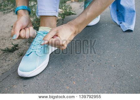 Close-up of girl ties the laces on the shoes while walking around the city