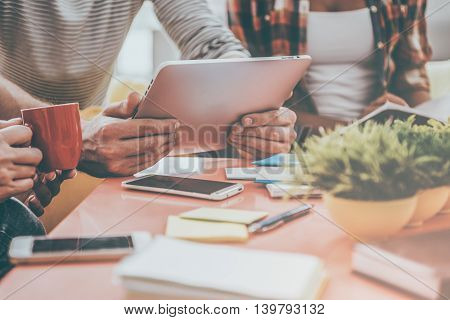 Close-up at work. Close-up of three young people working together while sitting at their working place