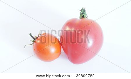 Tomato in the form Serce and round tomatoes lying on a white background