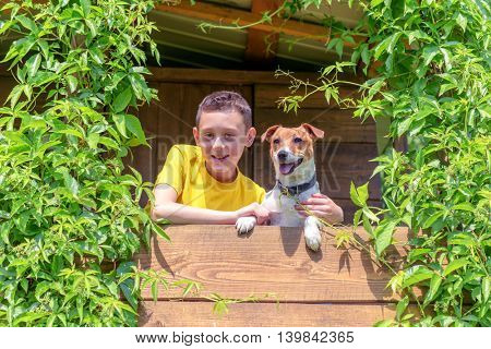 Smiling boy with dog on treehouse. Summer time!