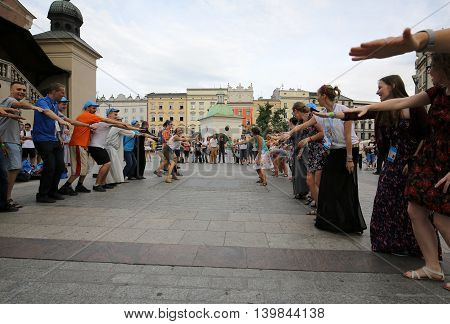 CRACOW POLAND - JULY 24 2016: Pilgrims of World Youth Day sing and dance on the Main Square in Cracow. Poland