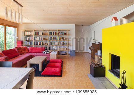 Living room of an eco house, red divan and fireplace
