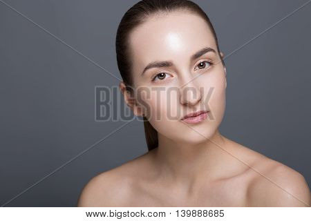 Beauty fashion vogue style face of caucasian brunette with elegant make-up blue eyes natural lips touching perfect skin. Close-up studio portrait isolated. Black background with grey spot. Toned.