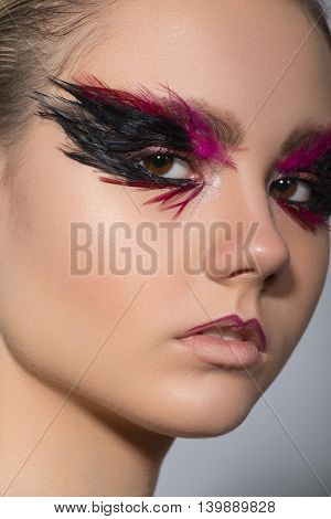beauty creative makeup with feathers on eyes macro closeup